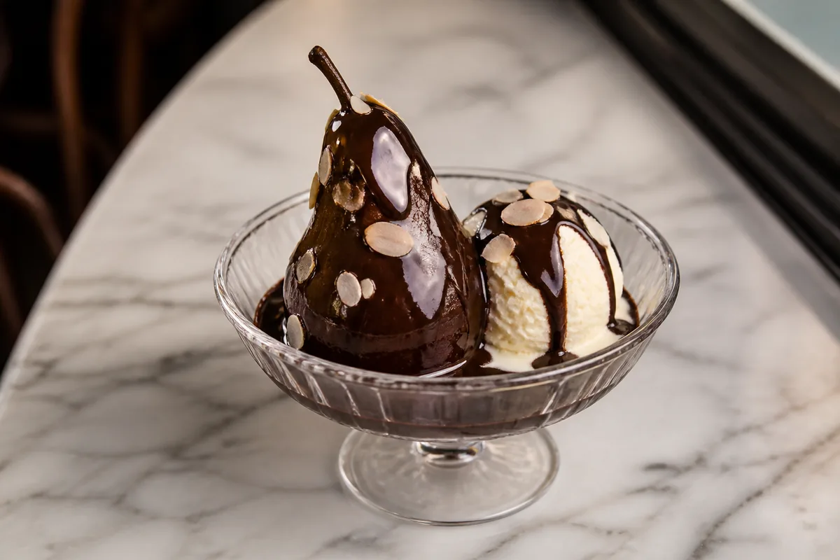 Une poire Belle-Hélène pochée avec chocolat, glace vanille et amandes